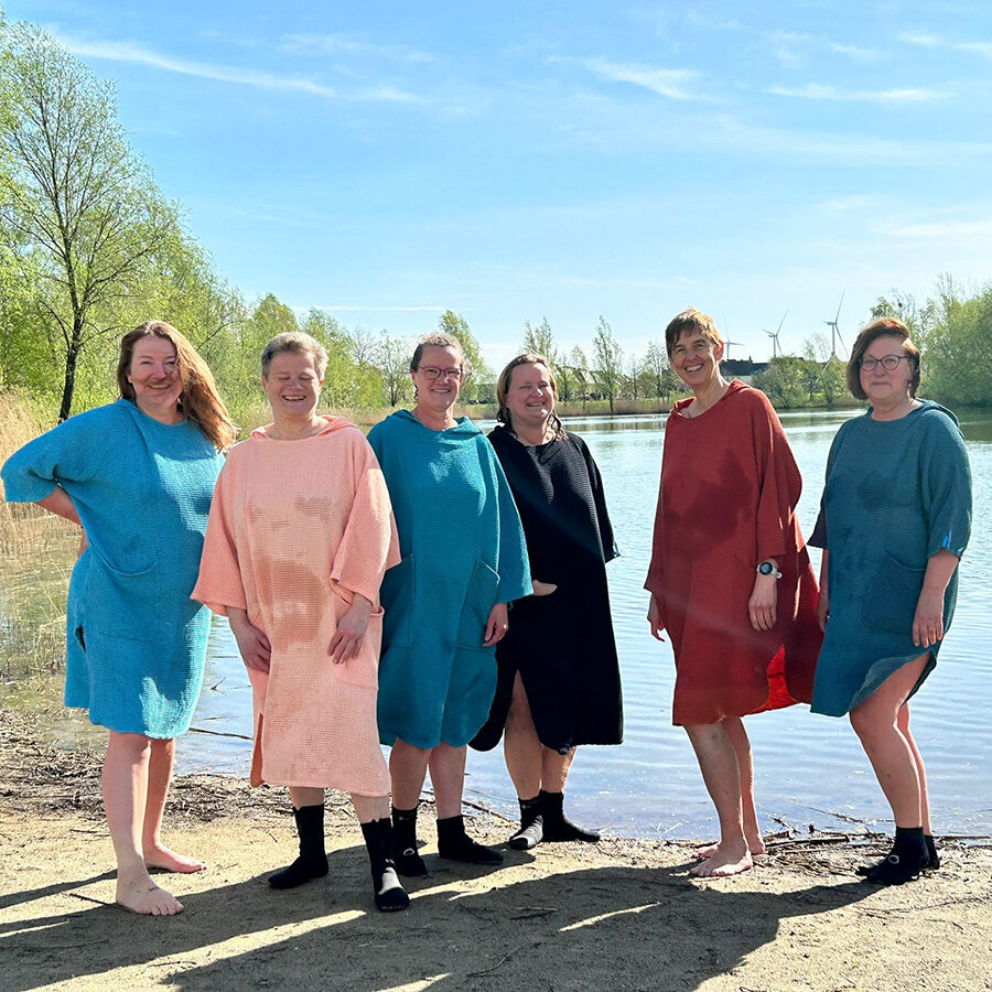 6 vrouwen voor een meer in hun omkleedponcho van zeemeermantel